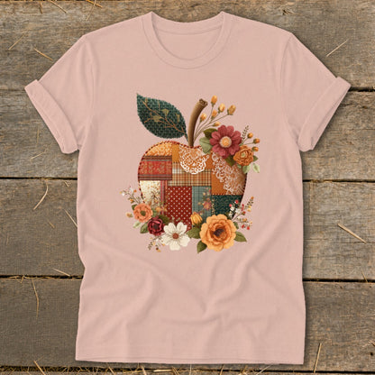 Pink t-shirt with patchwork apple graphic and floral accents.