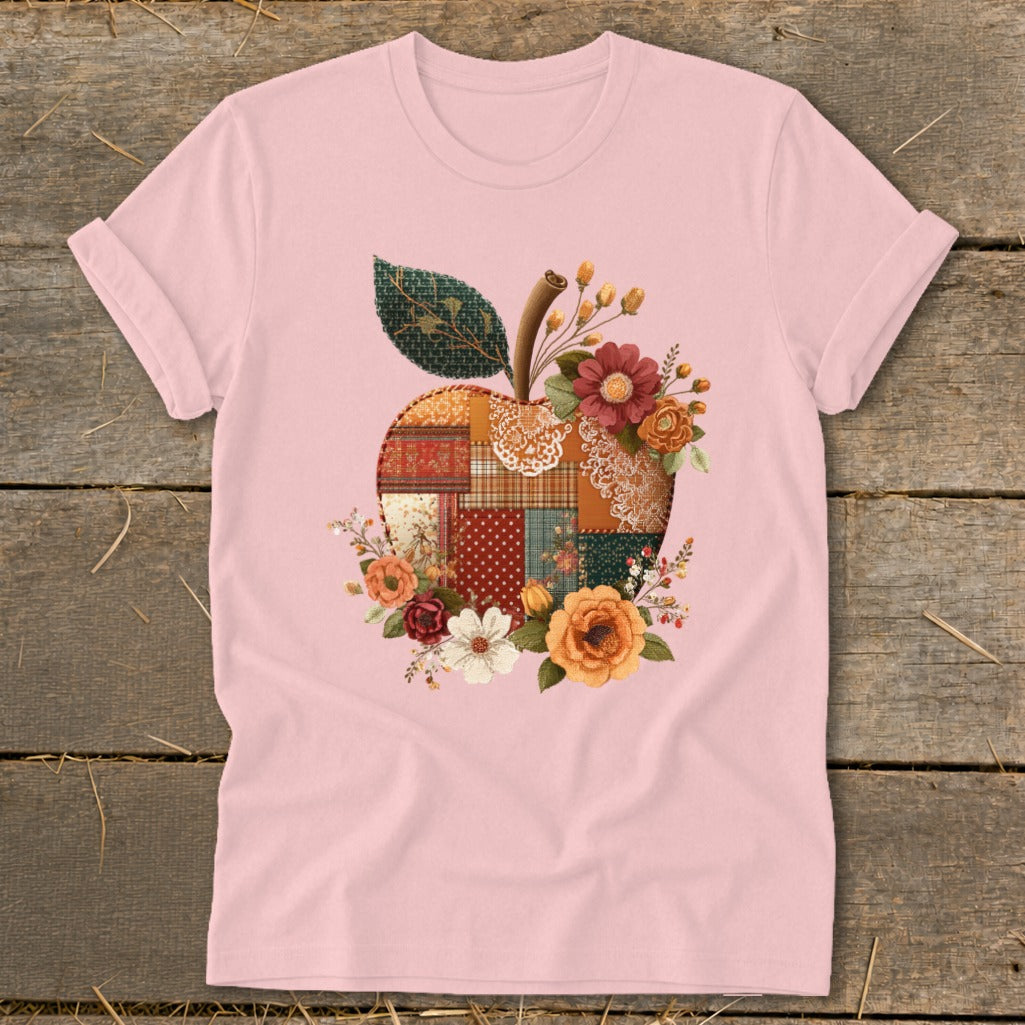 Pink t-shirt with a patchwork apple design filled with flowers and a leaf.