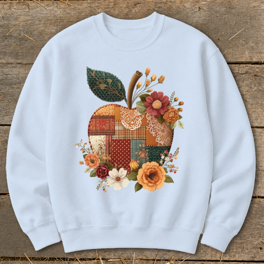 Light blue crewneck sweatshirt featuring a patchwork apple design with floral accents.