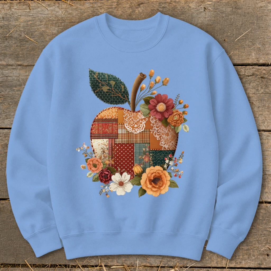 Light blue crewneck sweatshirt with a patchwork apple and floral design.