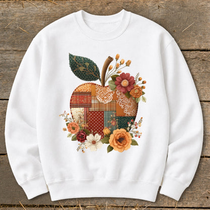 White sweatshirt with a patchwork apple design and floral accents.