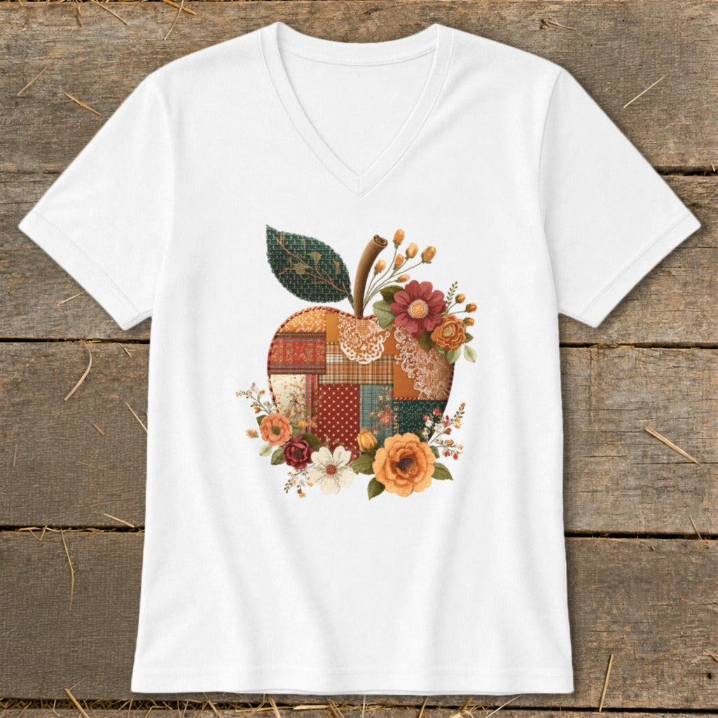 White t-shirt with a patchwork apple design adorned with flowers and leaves.