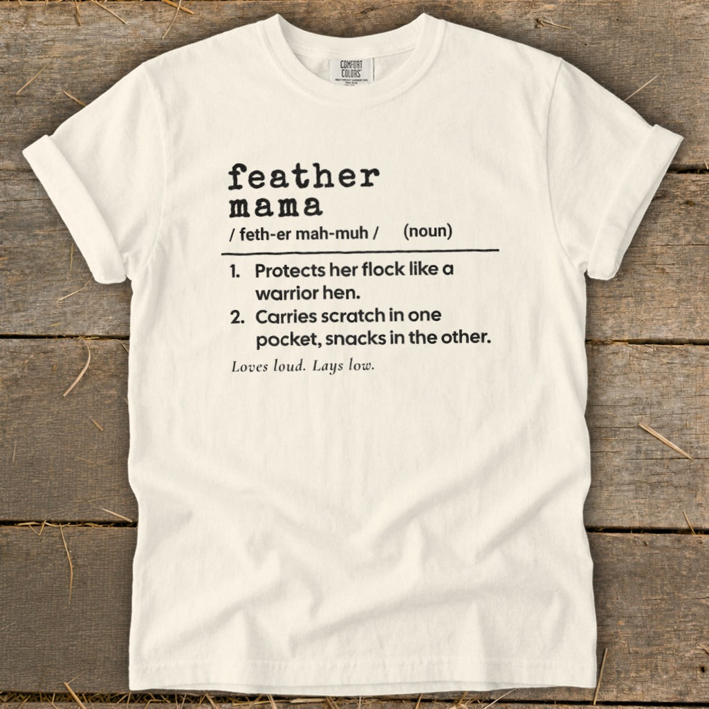 White t-shirt with black text defining "feather mama" and its characteristics.