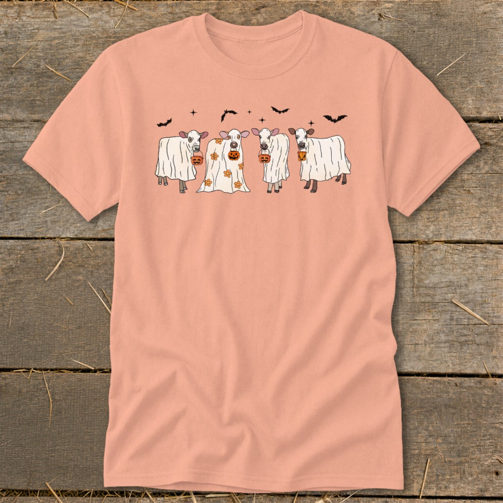 Four cows dressed as ghosts hold pumpkins under bats and stars.