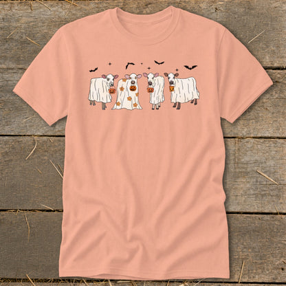 Four cows dressed as ghosts hold pumpkins under bats and stars.