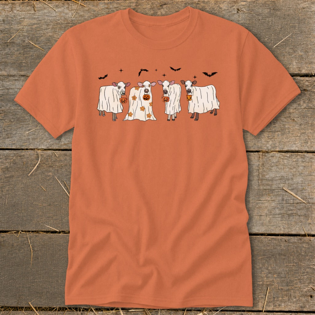 Four cows dressed as ghosts hold pumpkins; bats fly above.