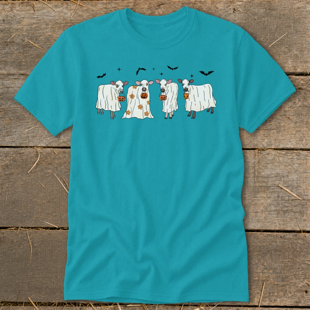 Four cows dressed as ghosts hold pumpkins under a sky with bats.