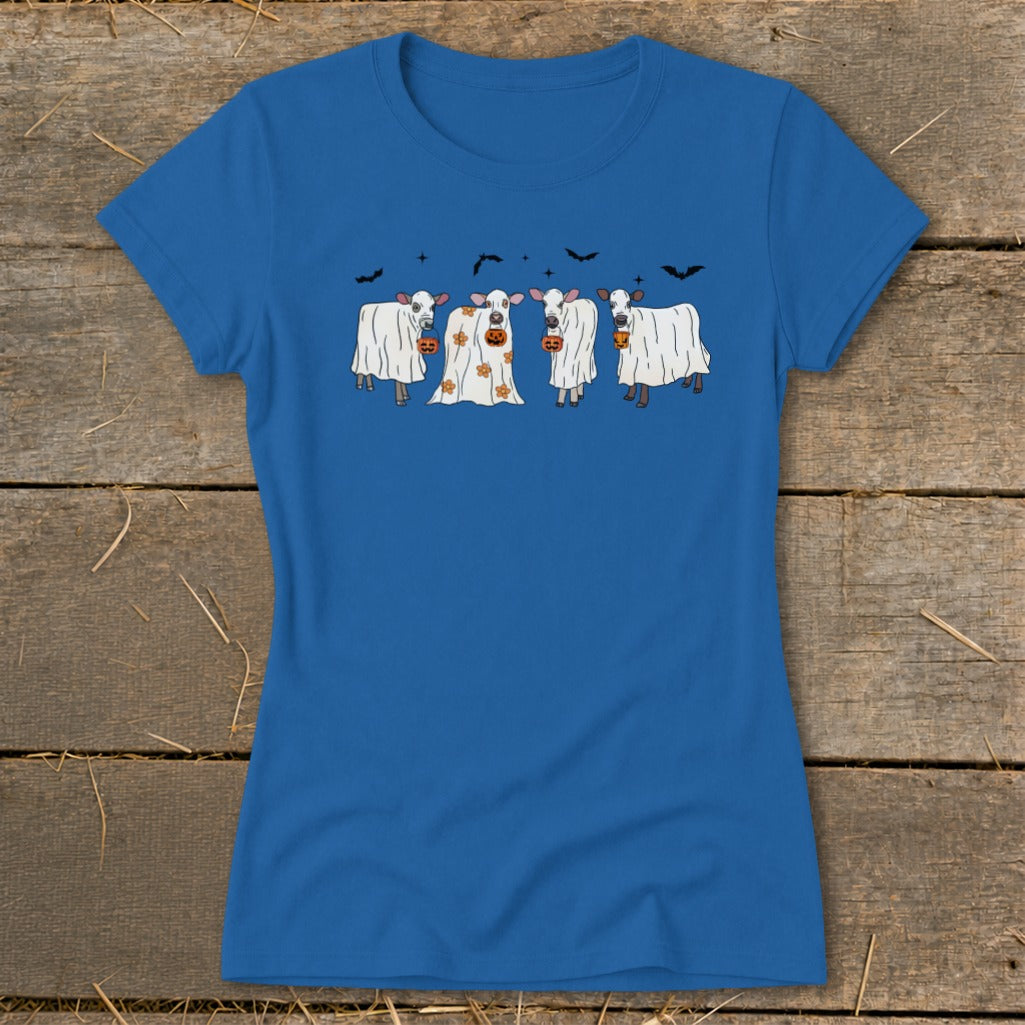 Four cows dressed as ghosts, holding pumpkins, with bats above.