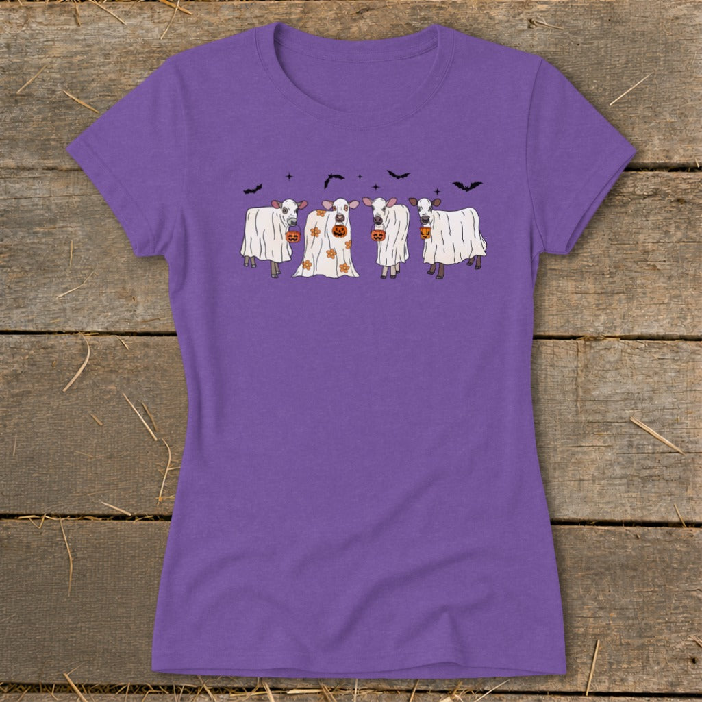 Four cows in ghost costumes holding jack-o'-lanterns with bats above.