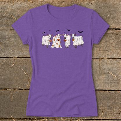 Four cows in ghost costumes holding jack-o'-lanterns with bats above.