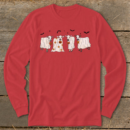 Four cows in ghost costumes holding pumpkins with bats above.