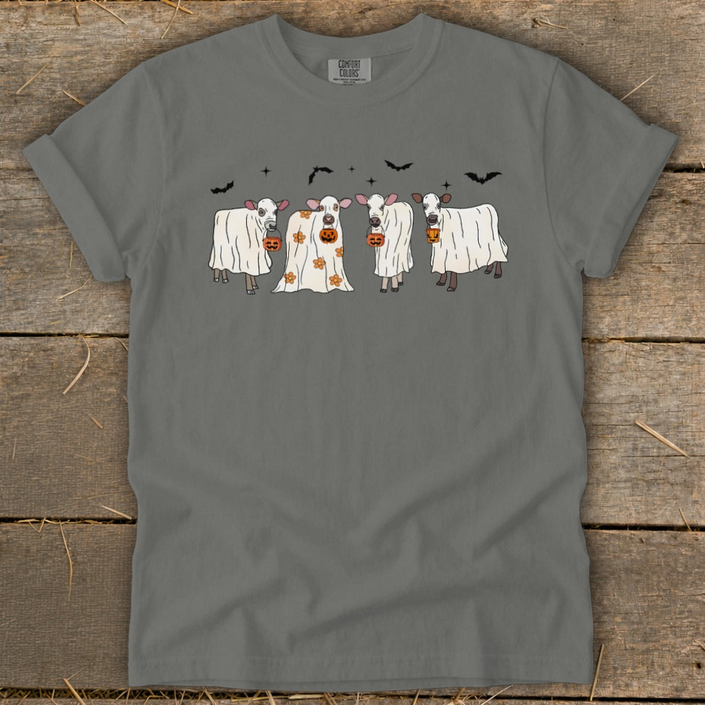 Four cows dressed as ghosts with pumpkins, flying bats above.