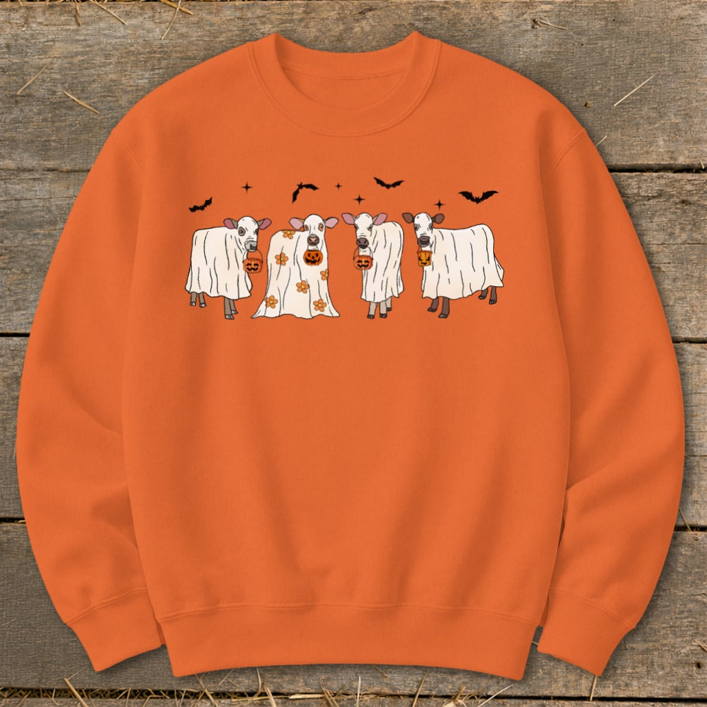 Four cows dressed as ghosts hold pumpkins on an orange sweatshirt.