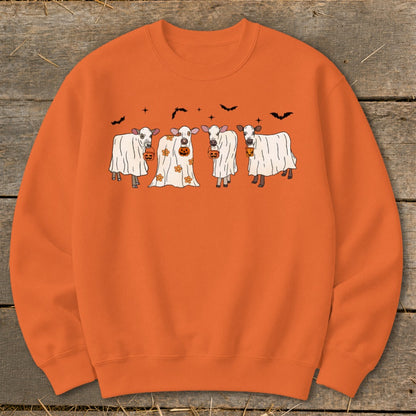 Four cows dressed as ghosts hold pumpkins on an orange sweatshirt.