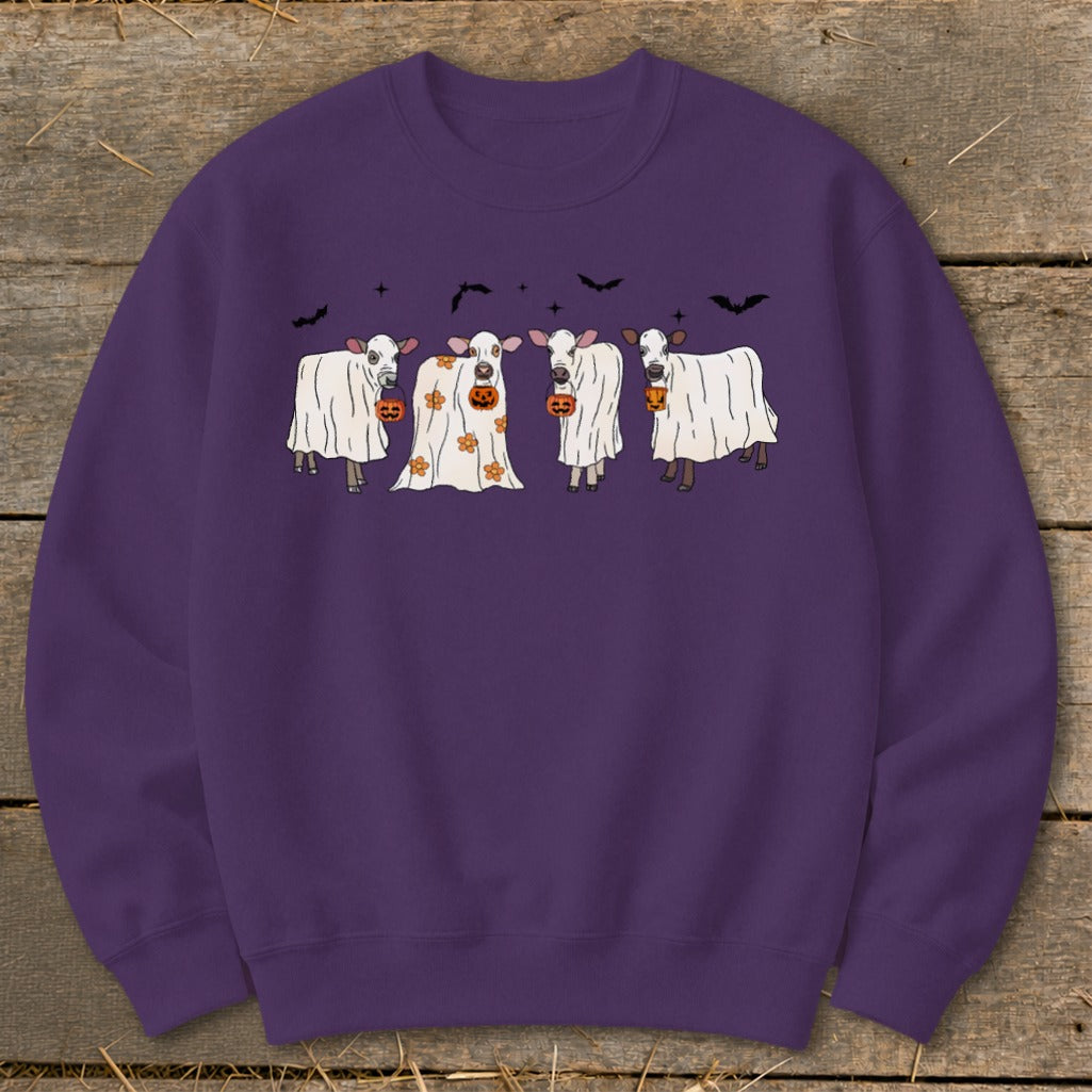 Four cows dressed as ghosts hold pumpkins against a dark background with bats.