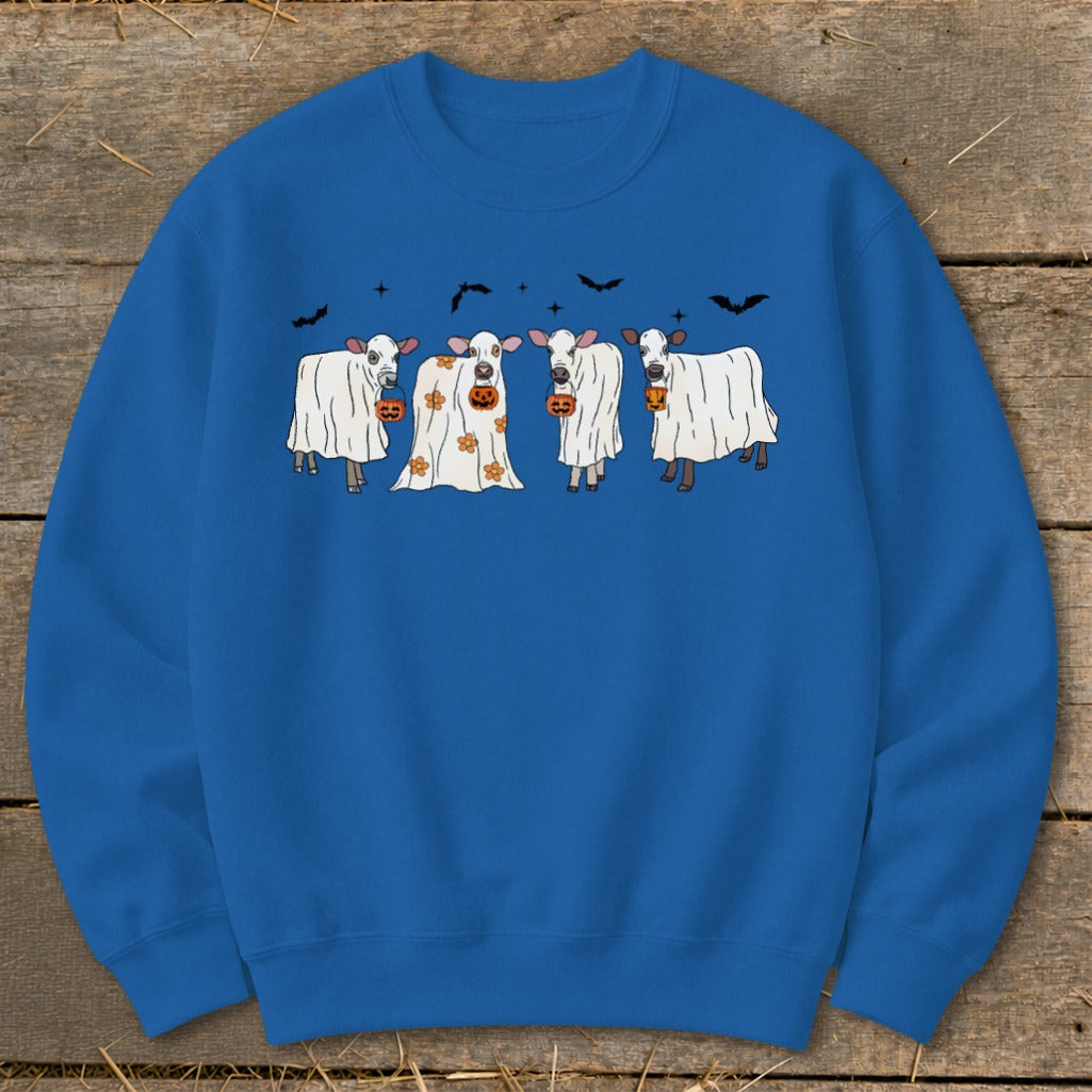 Four cows dressed as ghosts with pumpkins and bats for Halloween.