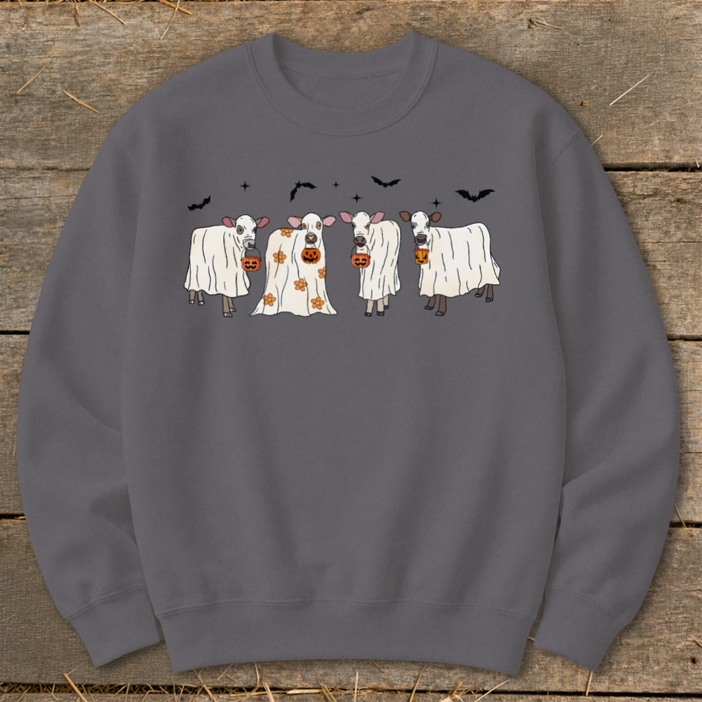 Four cows dressed as ghosts holding pumpkins, with bats in the background.