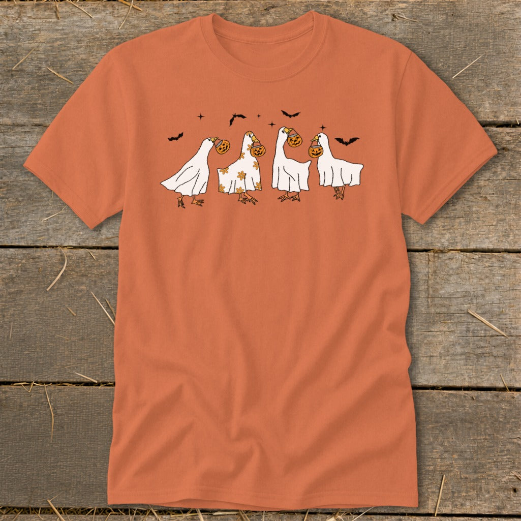 Four cartoon geese dressed as ghosts, carrying pumpkins, with bats above.