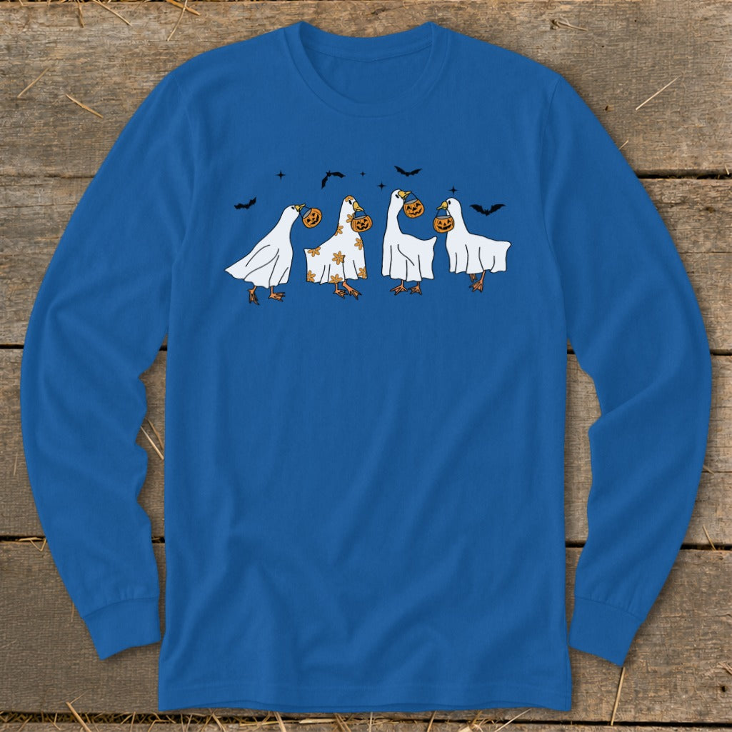 Four geese in ghost costumes carrying pumpkins with bats in the background.
