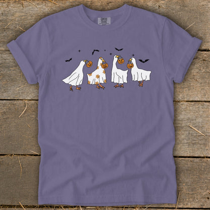 Four geese in ghost costumes carrying pumpkins on a purple t-shirt.