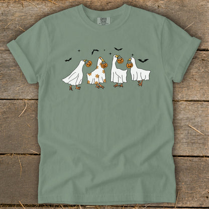 Green t-shirt with four cartoon geese in ghost costumes carrying pumpkins and bats.