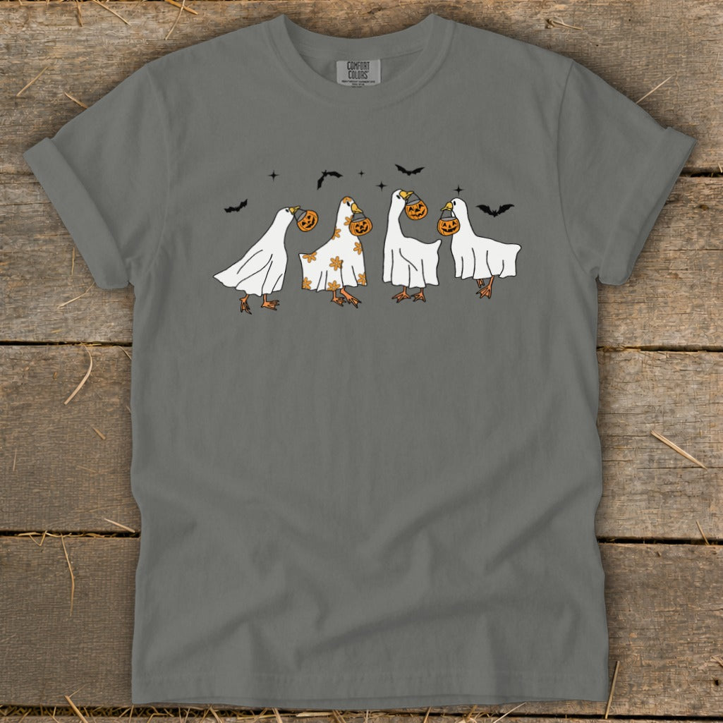 Ducks in ghost costumes holding pumpkins with bats in the sky.