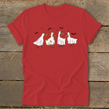 Four geese in ghost costumes carrying pumpkins and bats fly across a red shirt.