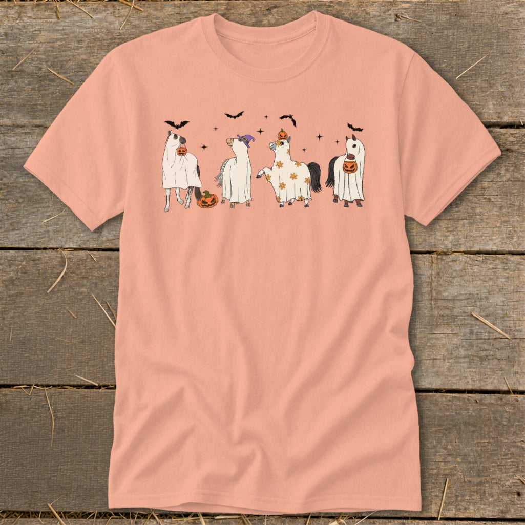 Four horses in ghost costumes with pumpkins and bats on a peach t-shirt.