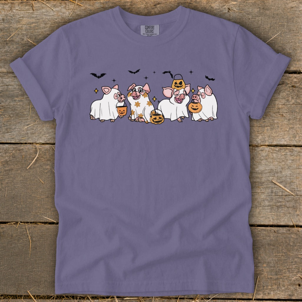 Five pigs dressed as ghosts with pumpkins and bats, on a purple t-shirt.