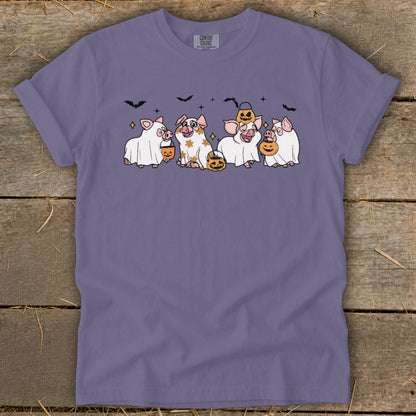 Five pigs dressed as ghosts with pumpkins and bats, on a purple t-shirt.
