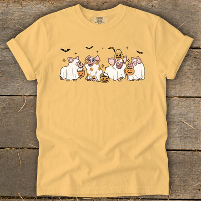 Yellow t-shirt with cartoon pigs dressed as ghosts holding pumpkins and candy buckets.