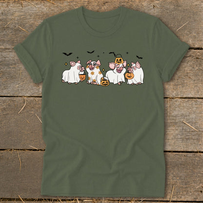 Five pigs in ghost costumes hold pumpkins with bats above them on a green t-shirt.
