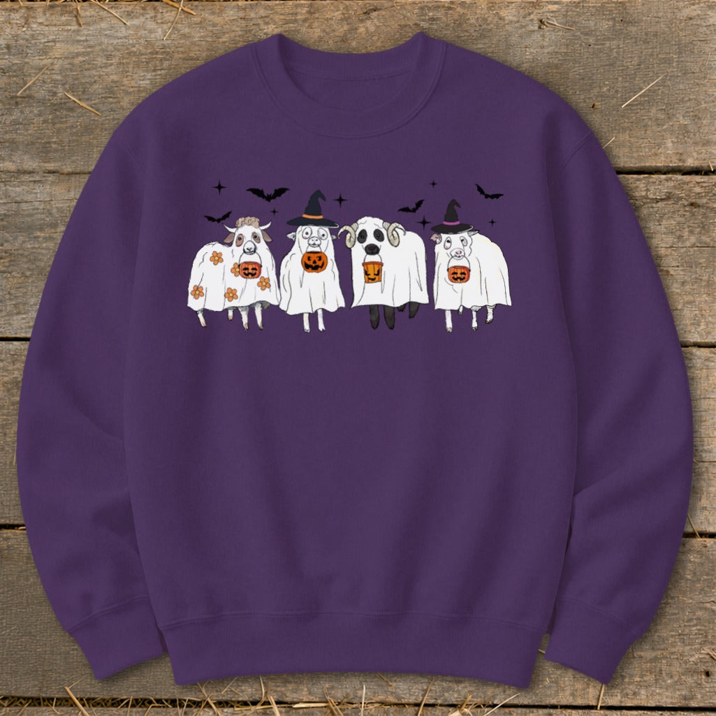 Four sheep in ghost costumes holding pumpkins with bats above.