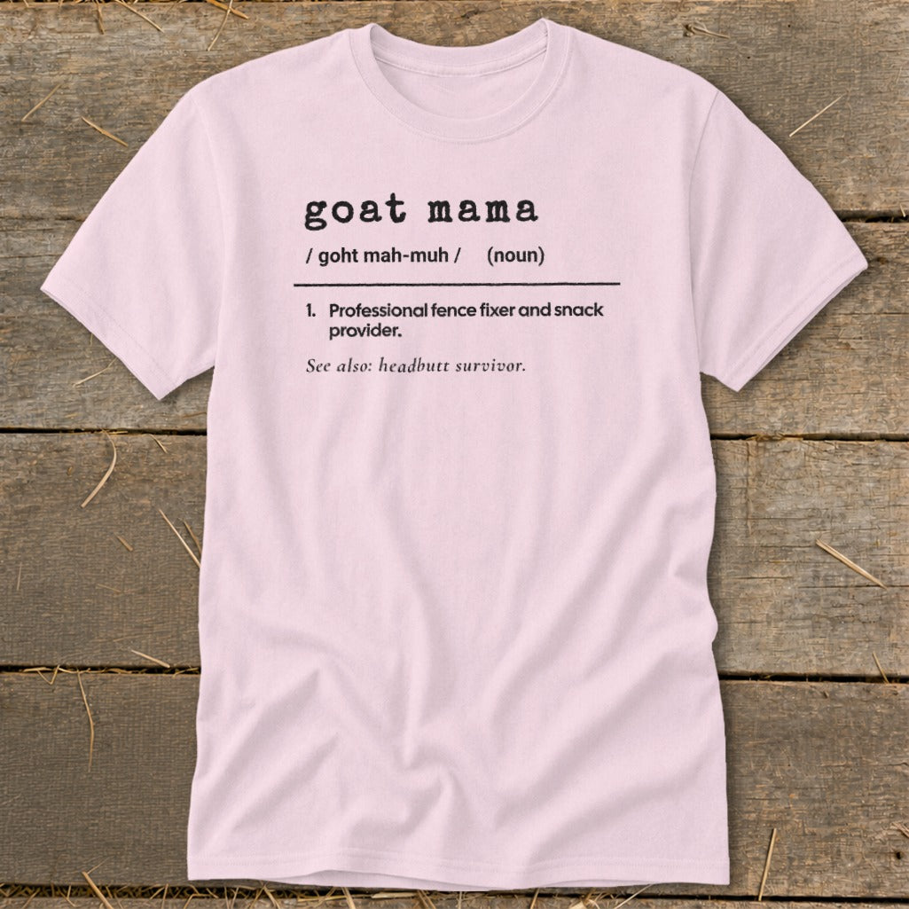 Light pink short-sleeve t-shirt with black dictionary-style text defining goat mama on a wooden background.