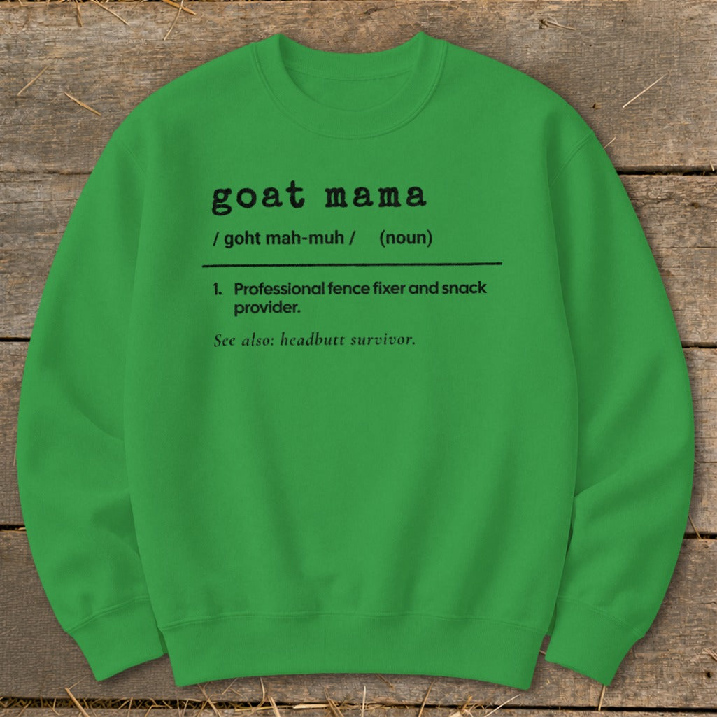Green crewneck sweatshirt printed with a humorous dictionary-style definition of goat mama on a wooden surface.