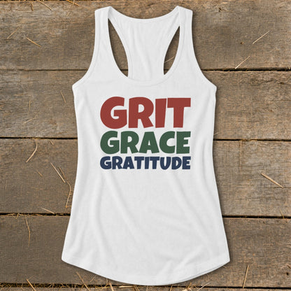 A white racerback tank top with the words Grit Grace Gratitude printed on the chest.