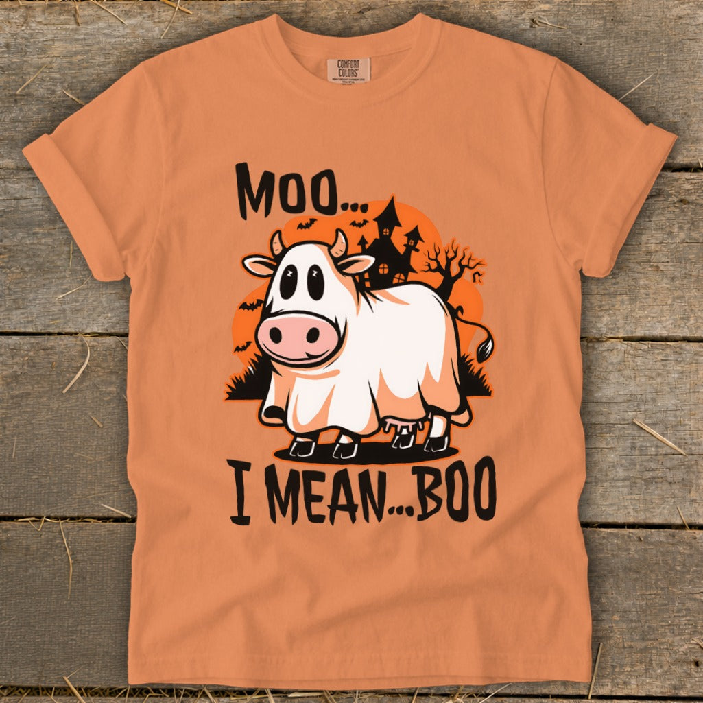 An orange t-shirt featuring a graphic of a cow in a ghost costume with the text Moo I Mean Boo.