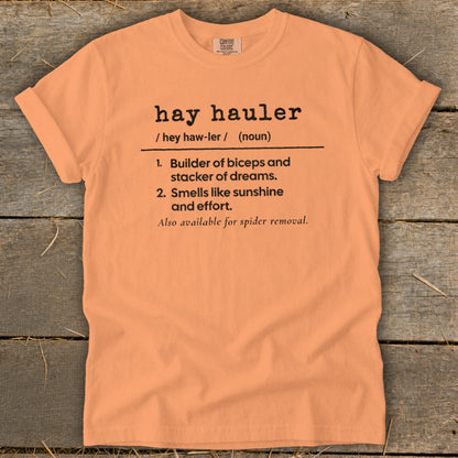 Peach t-shirt with black text defining "hay hauler" as a builder of biceps.