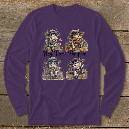 Purple long-sleeved t-shirt featuring a graphic of four cows in autumn hats, with the text Hay There, Pumpkin.