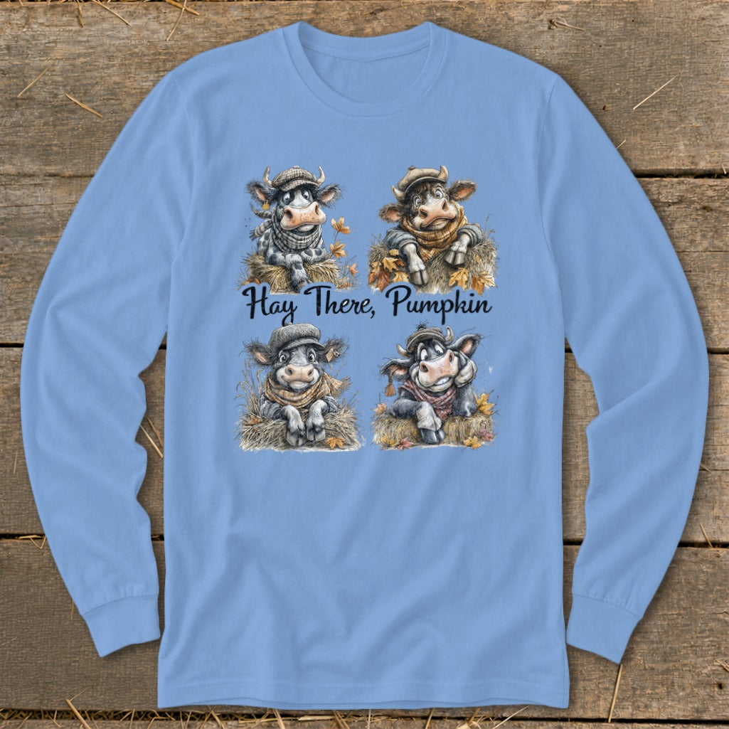 Four cartoon cows wearing scarves and hats sit in hay with autumn leaves, text says "Hay There, Pumpkin."