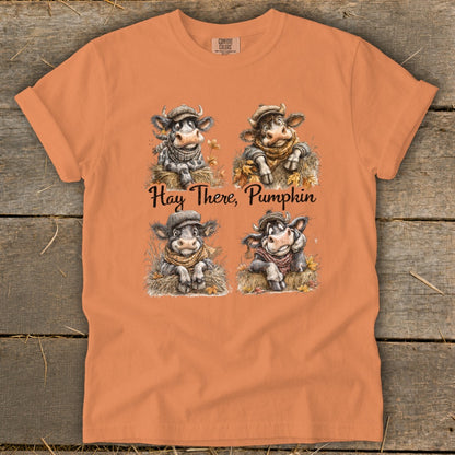 Orange t-shirt with four cartoon cows and the text "Hay There, Pumpkin."