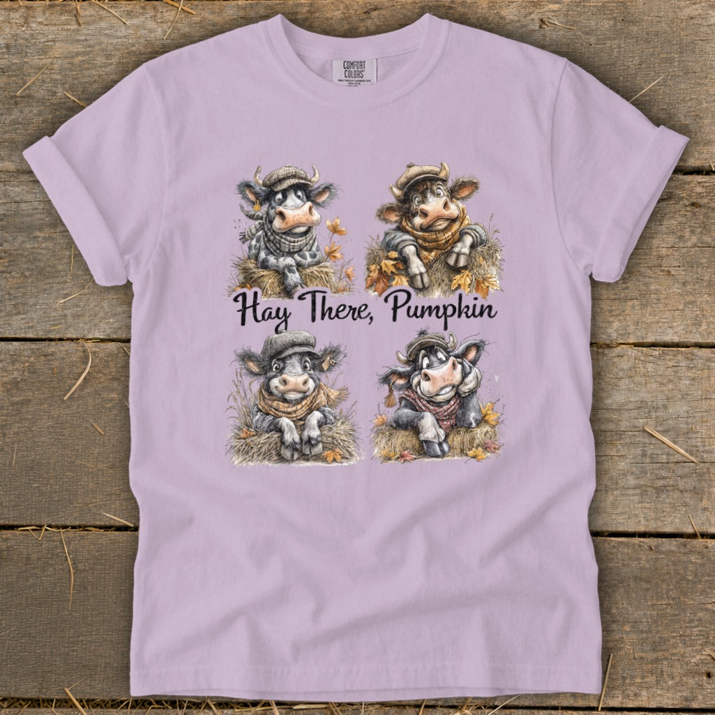 Four cute cows in hats and scarves on a lavender t-shirt with text "Hay There, Pumpkin".