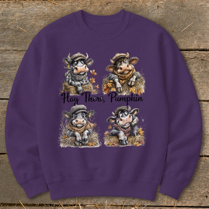 Four cartoon cows in hats and scarves sitting on hay, with text "Hay There, Pumpkin".