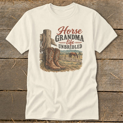An off-white t-shirt featuring a western graphic with cowboy boots, a horse, and the text Horse Grandma Life Unbridled.