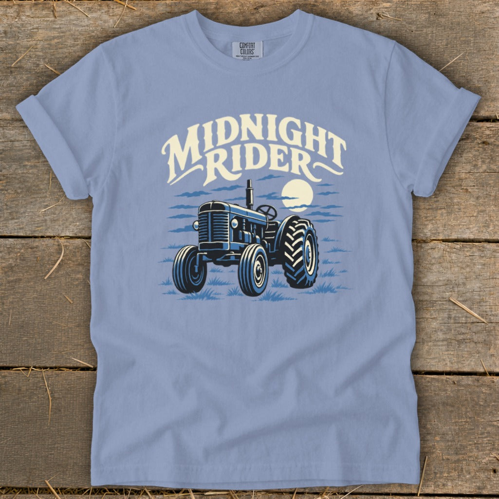 A periwinkle t-shirt featuring a graphic of a vintage tractor and the text Midnight Rider.