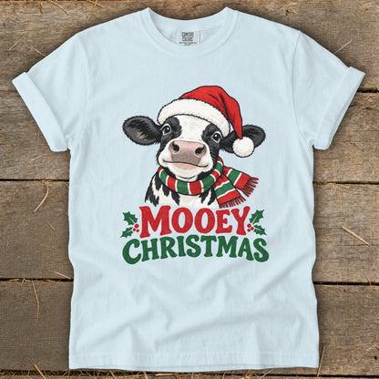 Light blue t-shirt with a cow wearing a Santa hat and striped scarf, saying "Mooey Christmas".