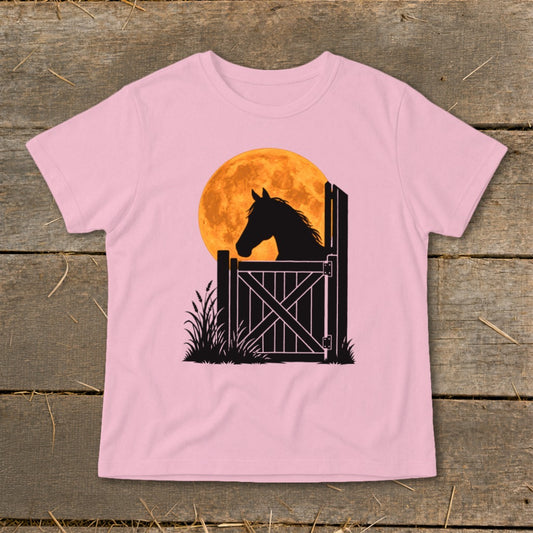 A pink t-shirt featuring a graphic of a horse silhouette looking over a gate against an orange moon.