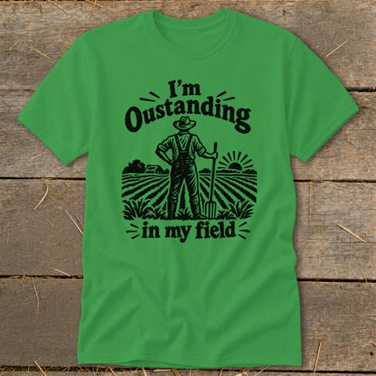 Green t-shirt with black graphic of a farmer in a field saying "I'm Oustanding in my field".