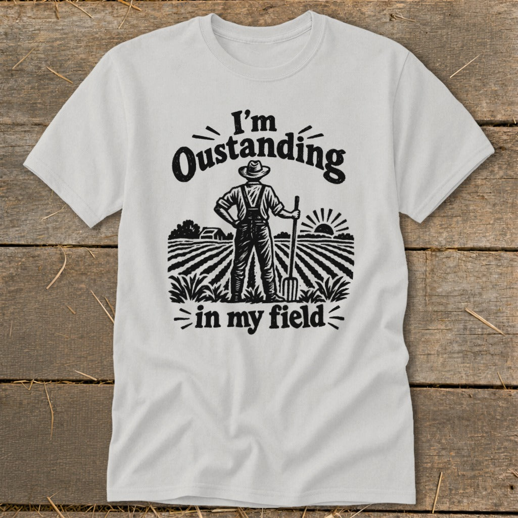 White t-shirt with black graphic of a farmer in a field with "I'm Oustanding in my field" text.