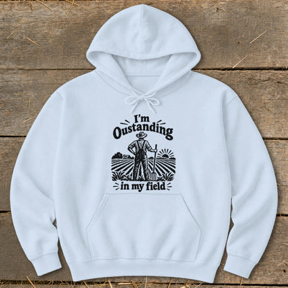 White hoodie with a graphic of a farmer standing in a field with the text "I'm Oustanding in my field".